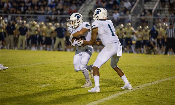 Summit High football player passes ball to teammate